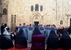 Szent János kápolna előtt miséznek, az örmények, a papok csukjában,a diakónusok kék ruhában. AZ örmény főpapok széken ülnek fejükön csukja van. A Szentsír templom udvarát szőnyeg fedi.                