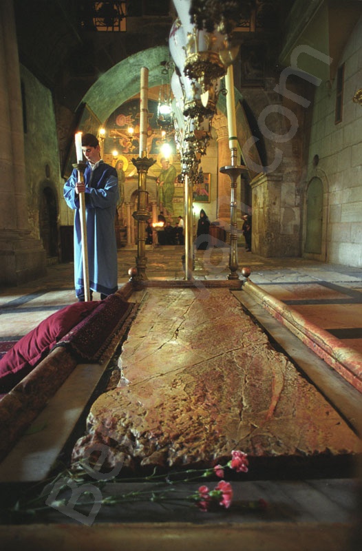 Szentsír templomban a bebalzsamozás kövénél  örmény szerzetes várja a patriarchát. A bebalzsamozás köve felett nyolc lámpa van. A megkenés kövét eltakaró márvány lap mellett virág van.                