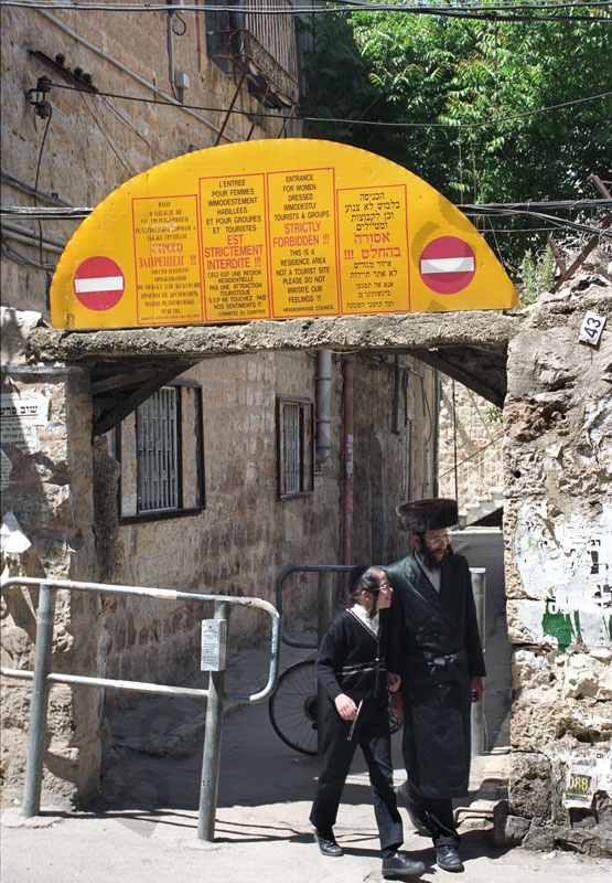   Apa és fia távozik Jeruzsálem ultraortodox zsidó negyede legkonzervatívabb kolóniájából. A bejárat felett több nyelven figyelmeztetik a turistákat, hogy ne zavarják az ott élőket.                   