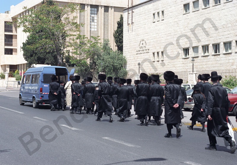   Izrael fővárosában Jeruzsálemben az ultraortodox zsidó negyedben ortodox zsidók temetési menete vonul. A fekete ünnepi ruhában vonuló menet elején a koporsót vivő kocsi mögött a fehér kaftános rabbi